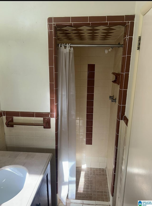 bathroom featuring vanity, a shower stall, tile walls, and a wainscoted wall