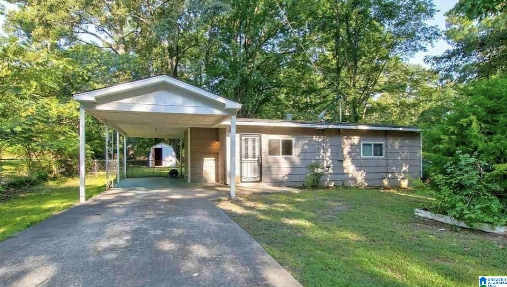 view of front facade with a carport, fence, a front yard, and aphalt driveway