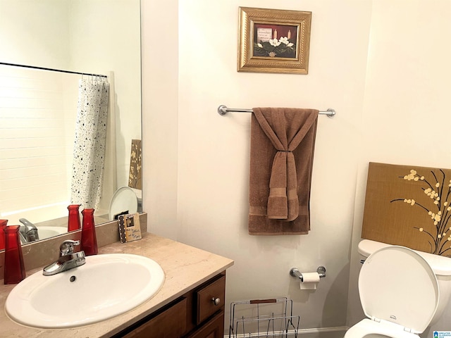 bathroom featuring curtained shower, toilet, and vanity