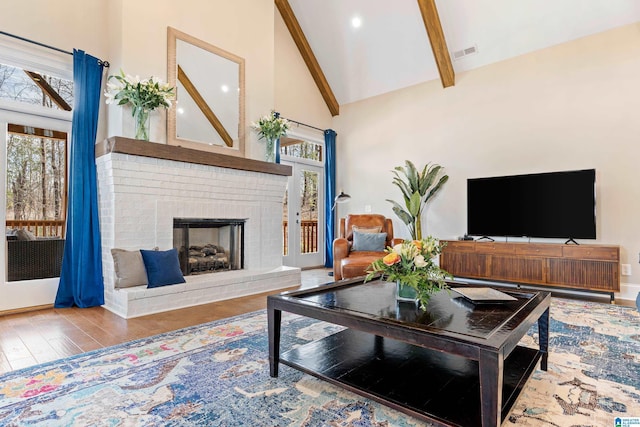 living room featuring beam ceiling, visible vents, a wealth of natural light, and high vaulted ceiling