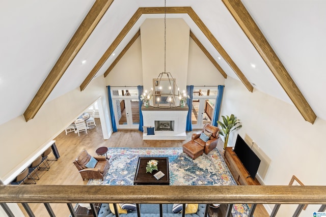 living room featuring beamed ceiling, a fireplace, an inviting chandelier, wood finished floors, and high vaulted ceiling