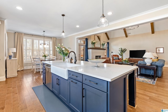 kitchen with a brick fireplace, dishwasher, light wood-type flooring, light countertops, and a sink