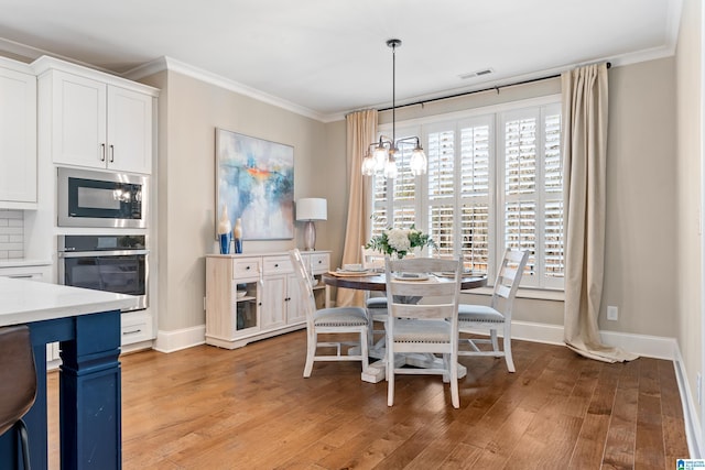 dining room with visible vents, light wood-style flooring, crown molding, and baseboards