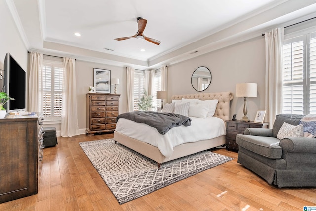 bedroom featuring visible vents, crown molding, light wood-type flooring, a tray ceiling, and recessed lighting