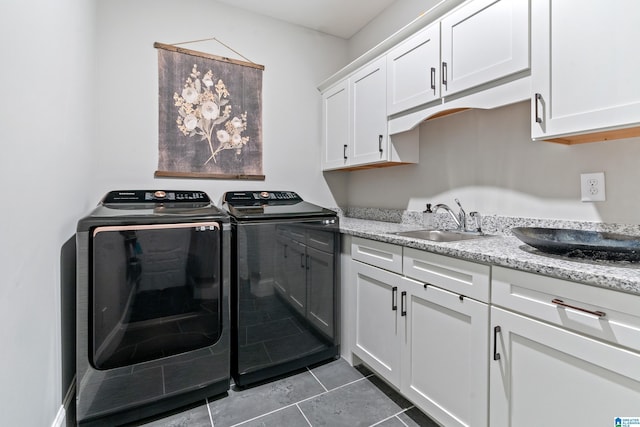 clothes washing area with washing machine and clothes dryer, cabinet space, and a sink