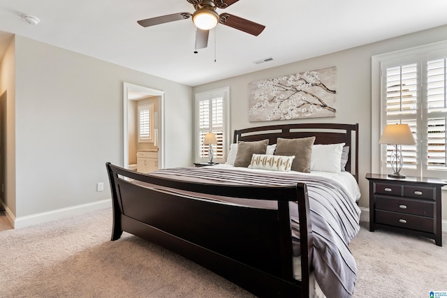 bedroom with visible vents, connected bathroom, baseboards, light colored carpet, and a ceiling fan