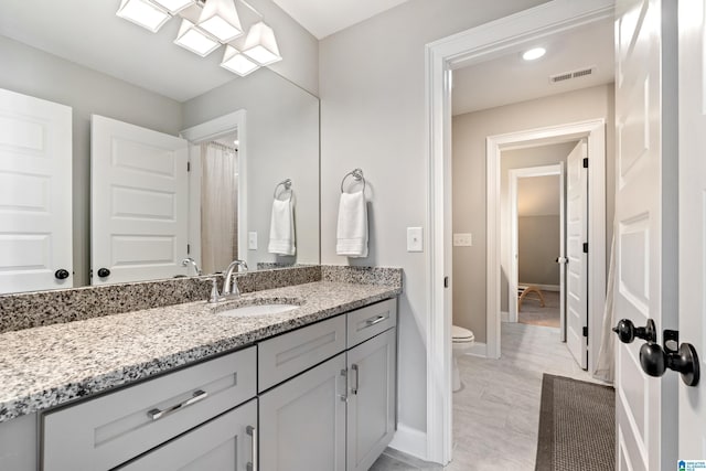 bathroom with vanity, toilet, baseboards, and visible vents