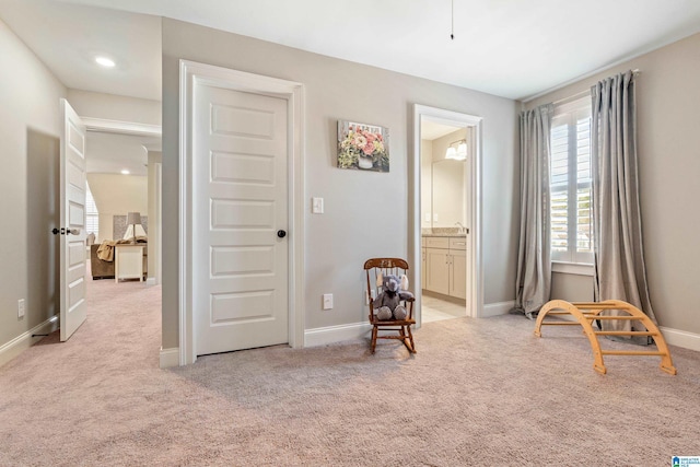 living area featuring light colored carpet and baseboards