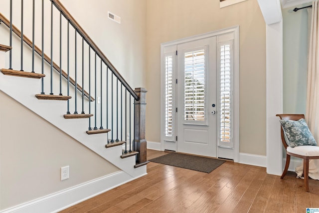 foyer with stairway, baseboards, visible vents, and wood finished floors