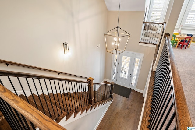 entrance foyer featuring an inviting chandelier, dark wood-type flooring, baseboards, and a towering ceiling