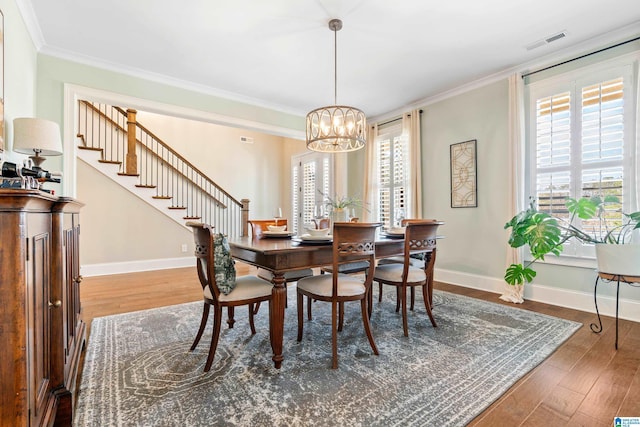 dining area featuring visible vents, ornamental molding, an inviting chandelier, and wood finished floors