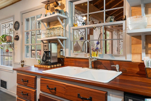 kitchen with visible vents, open shelves, butcher block countertops, a sink, and dishwasher