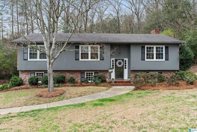 split foyer home featuring brick siding, a chimney, and a front yard