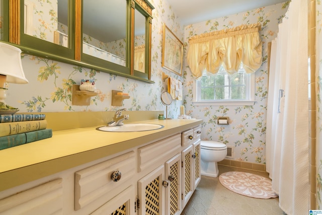 bathroom featuring vanity, baseboards, wallpapered walls, tile patterned flooring, and toilet