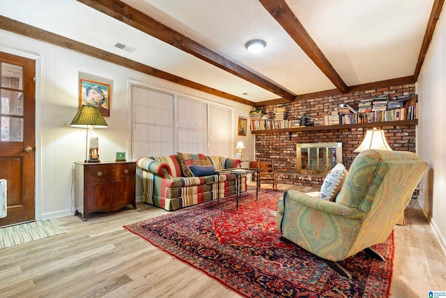 living area with visible vents, beam ceiling, baseboards, and wood finished floors