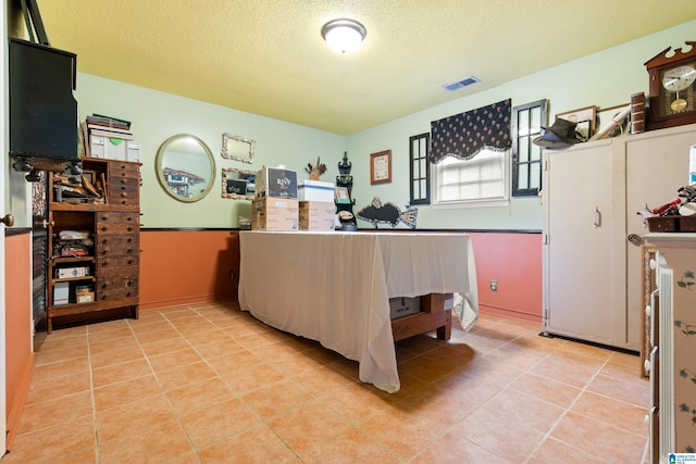 bedroom with light tile patterned floors, visible vents, and a textured ceiling