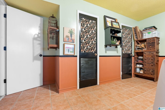 hall with light tile patterned flooring and a textured ceiling