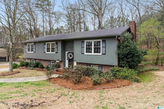 raised ranch featuring brick siding, a front lawn, and a chimney