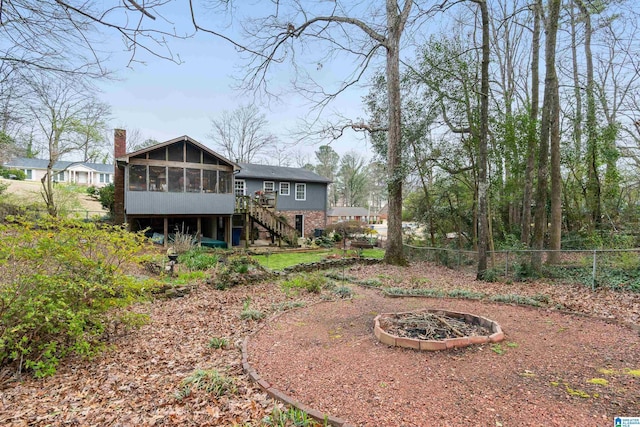 rear view of house featuring stairway, fence, a sunroom, and a chimney