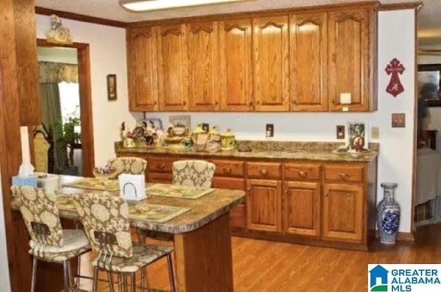 kitchen featuring a kitchen bar, brown cabinetry, and light wood finished floors