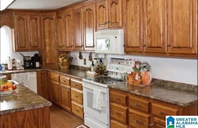 kitchen featuring white appliances, brown cabinets, and light wood-type flooring