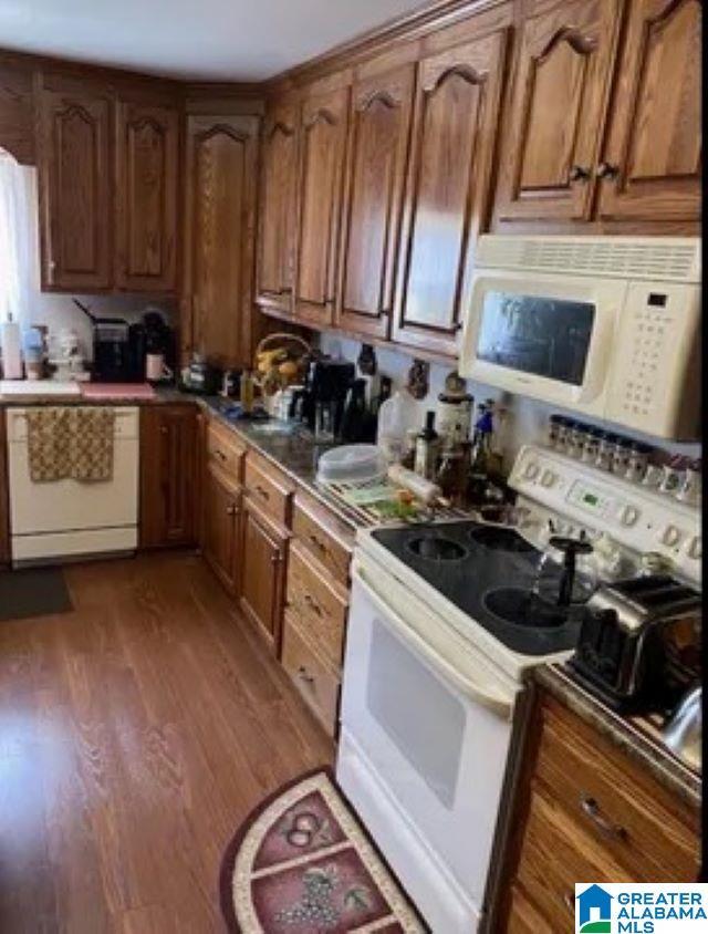 kitchen featuring light wood-type flooring, white appliances, and brown cabinets