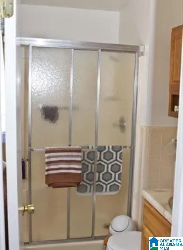 bathroom with vanity, toilet, and a shower with door