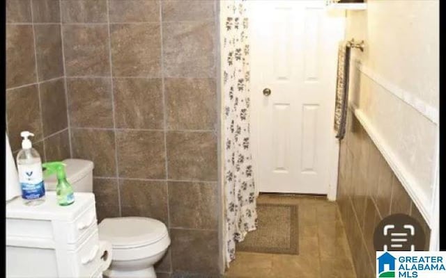 bathroom featuring tile patterned flooring, toilet, and tile walls