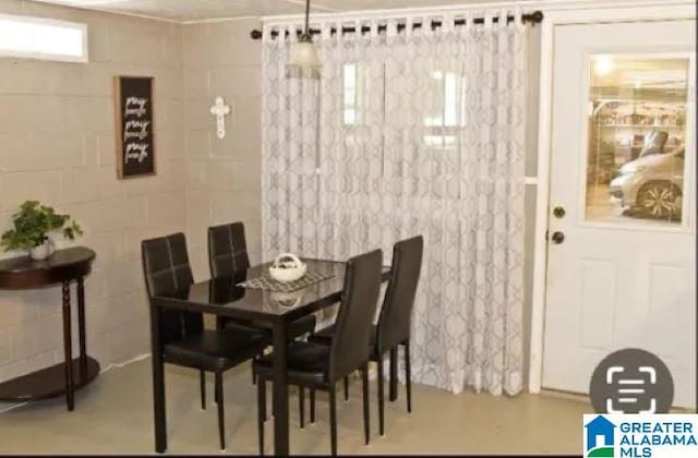 dining area featuring finished concrete flooring and concrete block wall