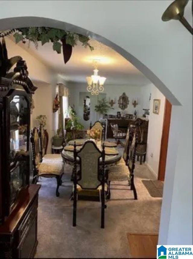 dining space with an inviting chandelier, arched walkways, and carpet floors