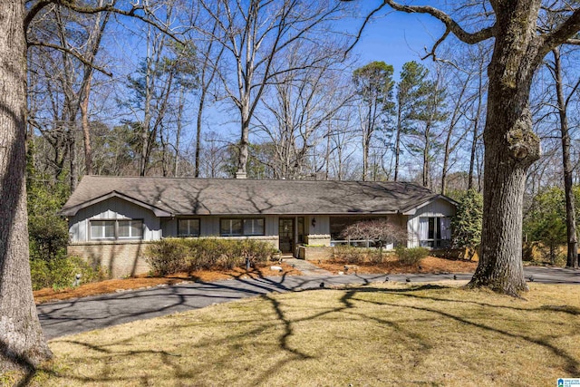 view of front of property featuring brick siding, board and batten siding, and a front lawn