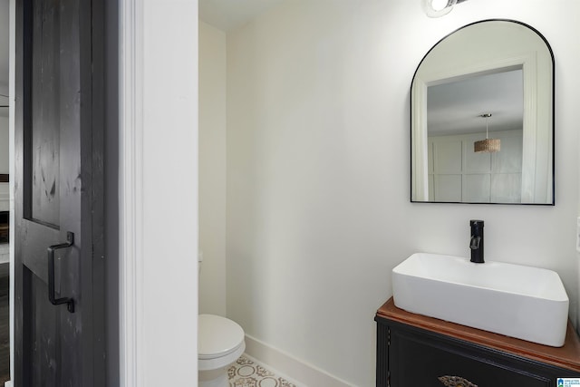 bathroom featuring toilet, vanity, and baseboards