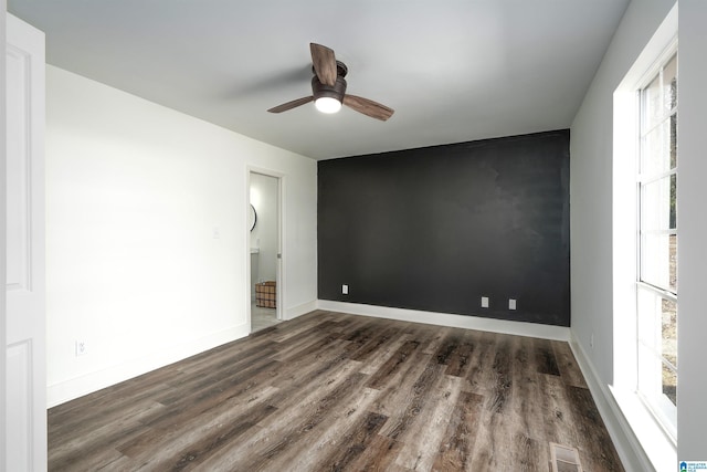 spare room featuring visible vents, baseboards, wood finished floors, and an accent wall