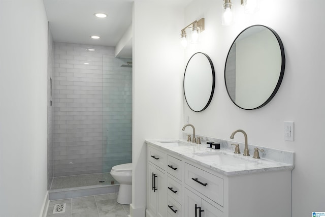 bathroom with a sink, tiled shower, toilet, and double vanity