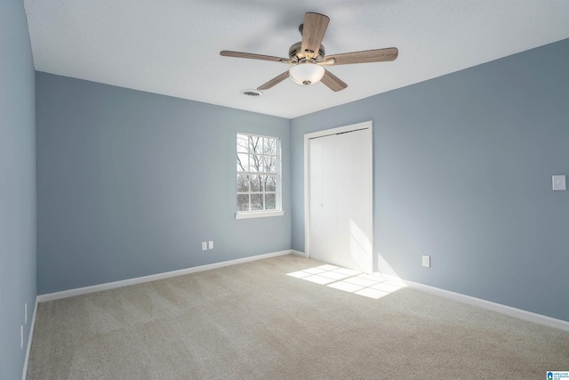 unfurnished bedroom with baseboards, visible vents, carpet floors, ceiling fan, and a closet