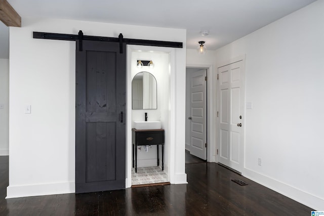 interior space with a barn door, wood finished floors, and baseboards