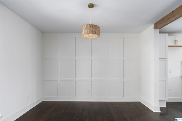 empty room featuring beamed ceiling, baseboards, dark wood-style flooring, and a decorative wall