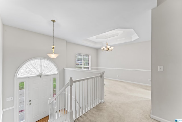 foyer entrance with a tray ceiling, a notable chandelier, carpet flooring, and baseboards