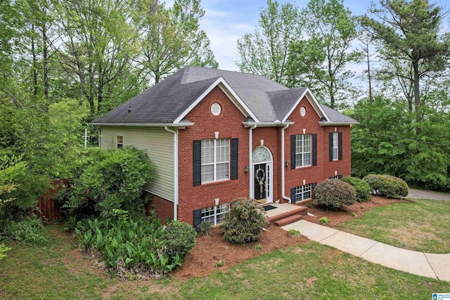 view of front of property featuring brick siding, fence, a front yard, and roof with shingles