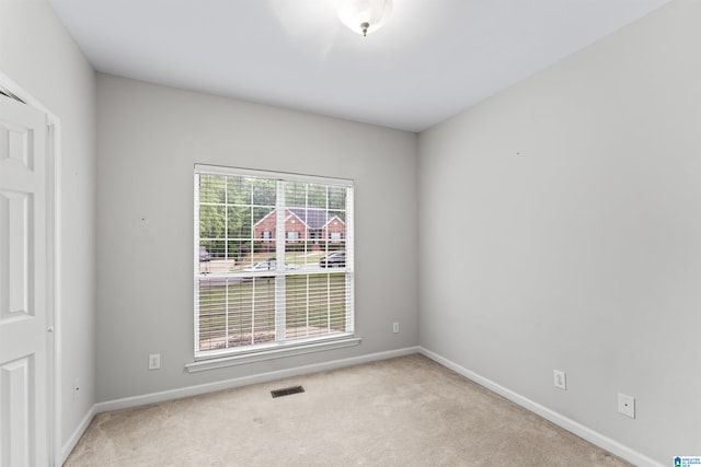 carpeted spare room featuring visible vents and baseboards