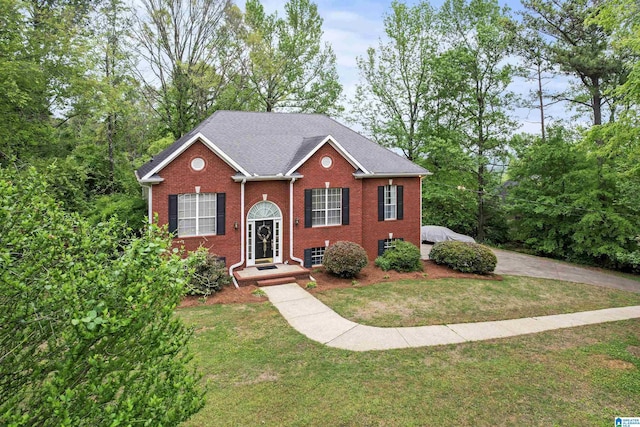 view of front of home with a front lawn, brick siding, and roof with shingles