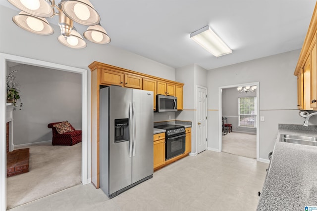 kitchen featuring light carpet, a sink, appliances with stainless steel finishes, an inviting chandelier, and light countertops