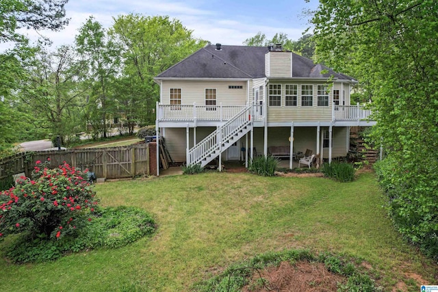 back of property with fence, a wooden deck, a yard, a sunroom, and stairs