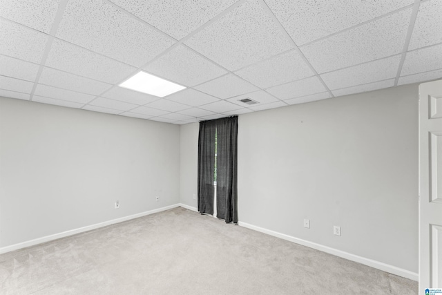 empty room featuring a drop ceiling, baseboards, light carpet, and visible vents