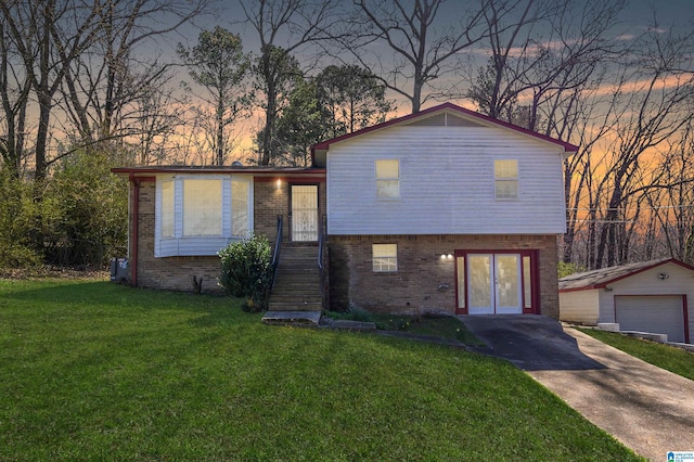 tri-level home featuring driveway, brick siding, an outdoor structure, and a front lawn