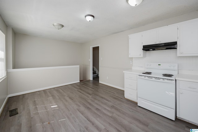 kitchen featuring under cabinet range hood, light wood-type flooring, light countertops, decorative backsplash, and electric stove