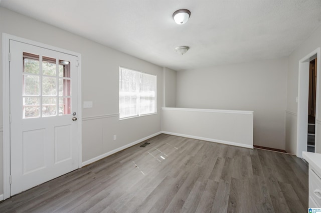 unfurnished dining area with visible vents, baseboards, and wood finished floors