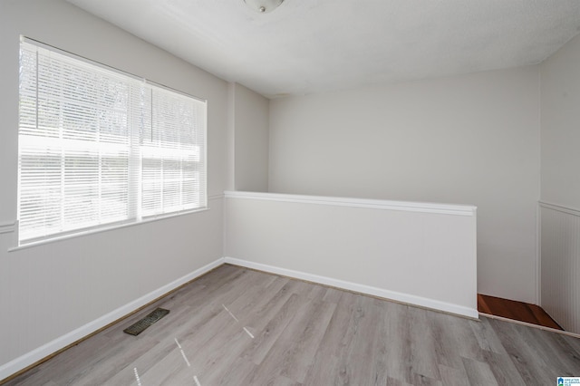 empty room with visible vents, baseboards, and wood finished floors