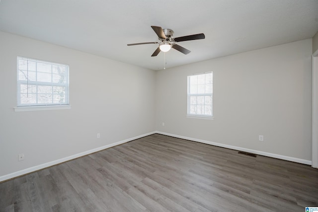 empty room featuring visible vents, ceiling fan, baseboards, and wood finished floors