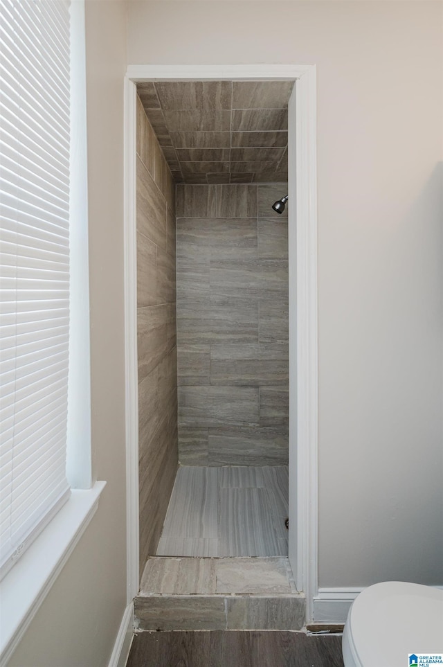 bathroom with baseboards, toilet, and a stall shower